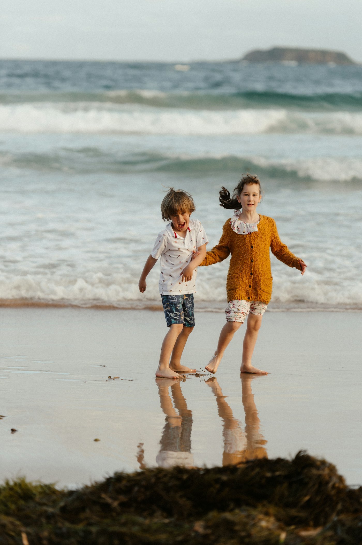 A brother and sister holding hands in the shallows