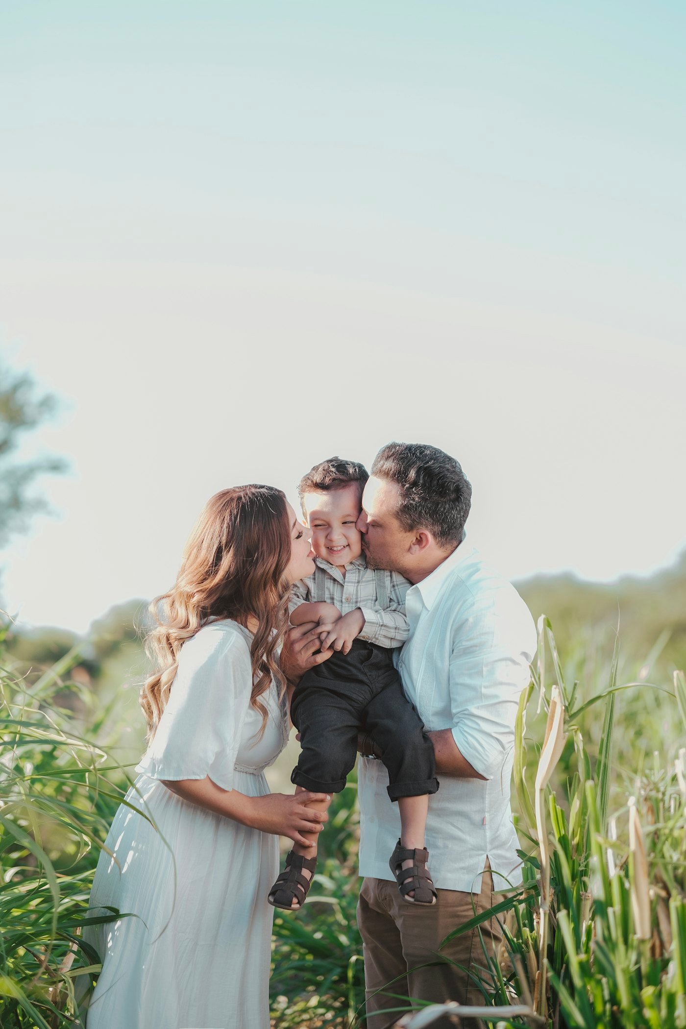 Parents kissing their son on both cheeks