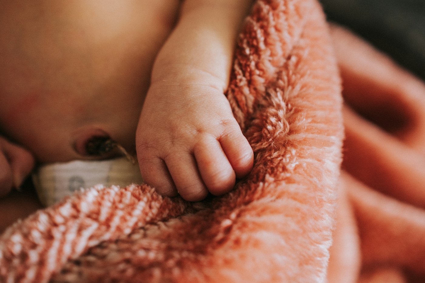 A tiny hand gripping a knitted blanket