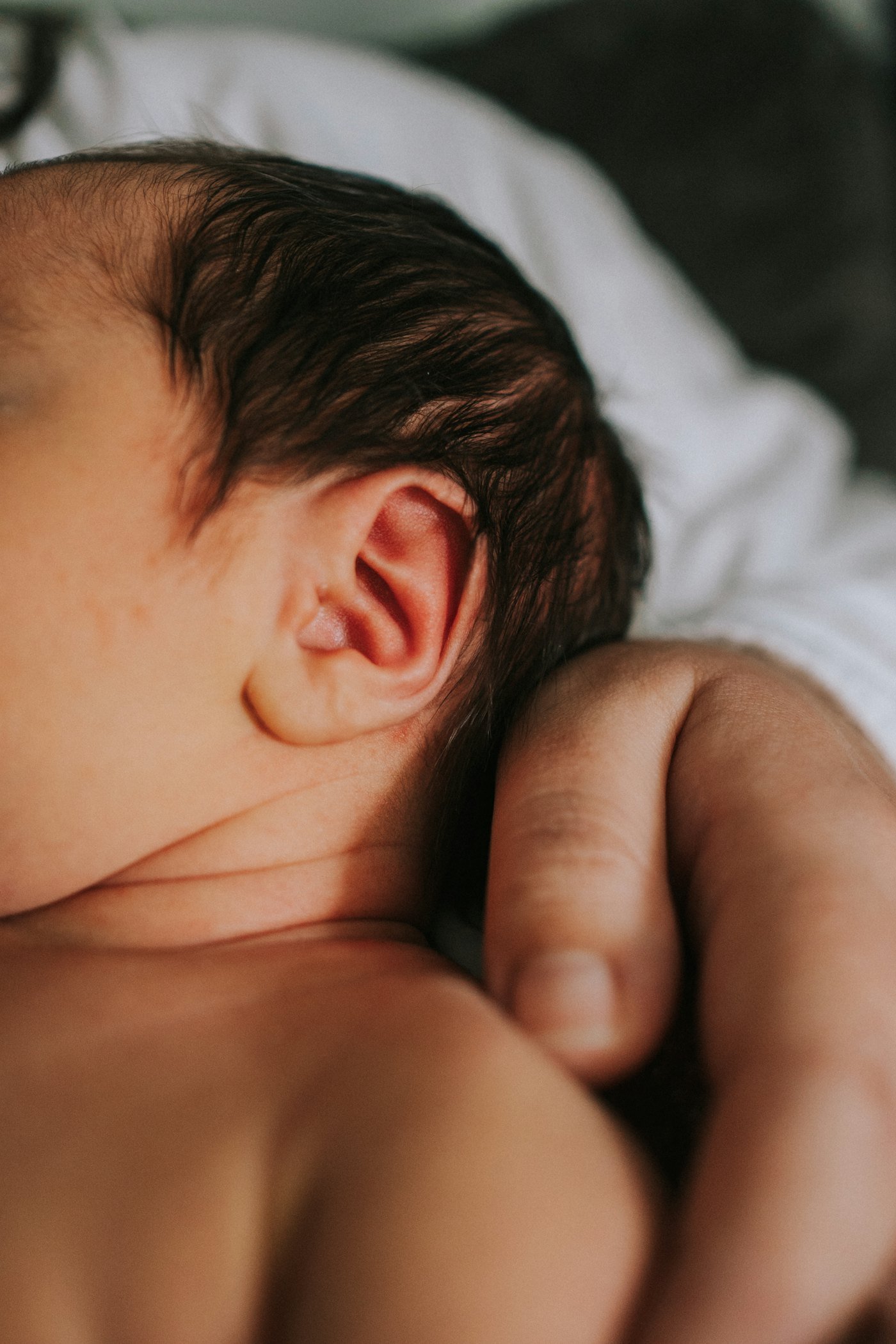 A newborn curled up against a parent’s chest