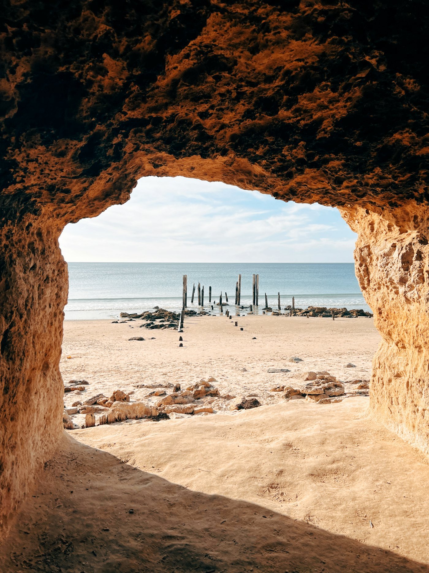 The jetty posts framed by the opening of a cliff cave